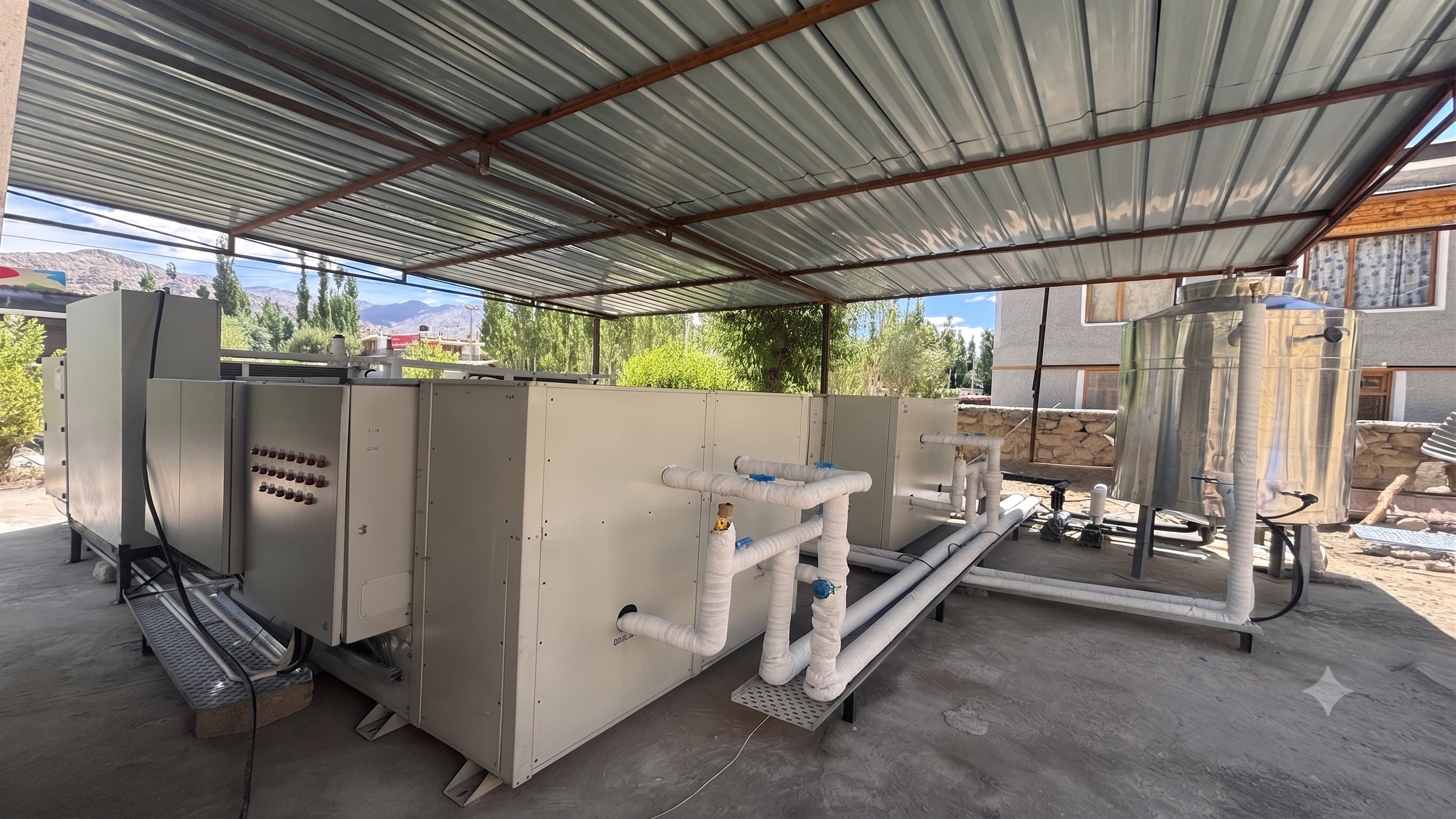 Outdoor heat pump units, buffer tank and insulated piping installed under the site canopy at Thiksey